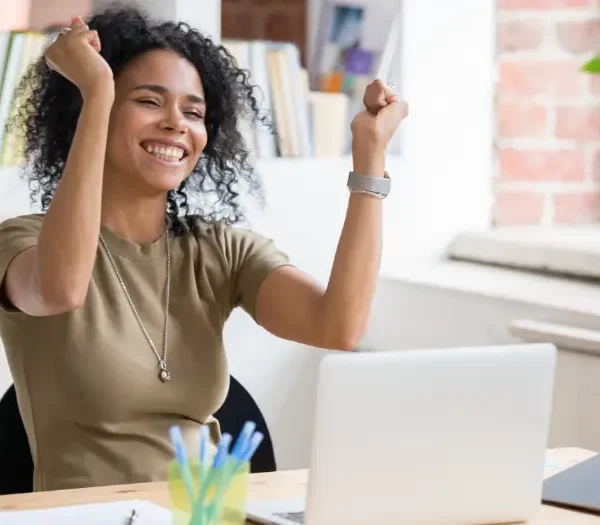 You woman raising her hands after getting an email from the CFAI communicasting she passed the CFA Exam!