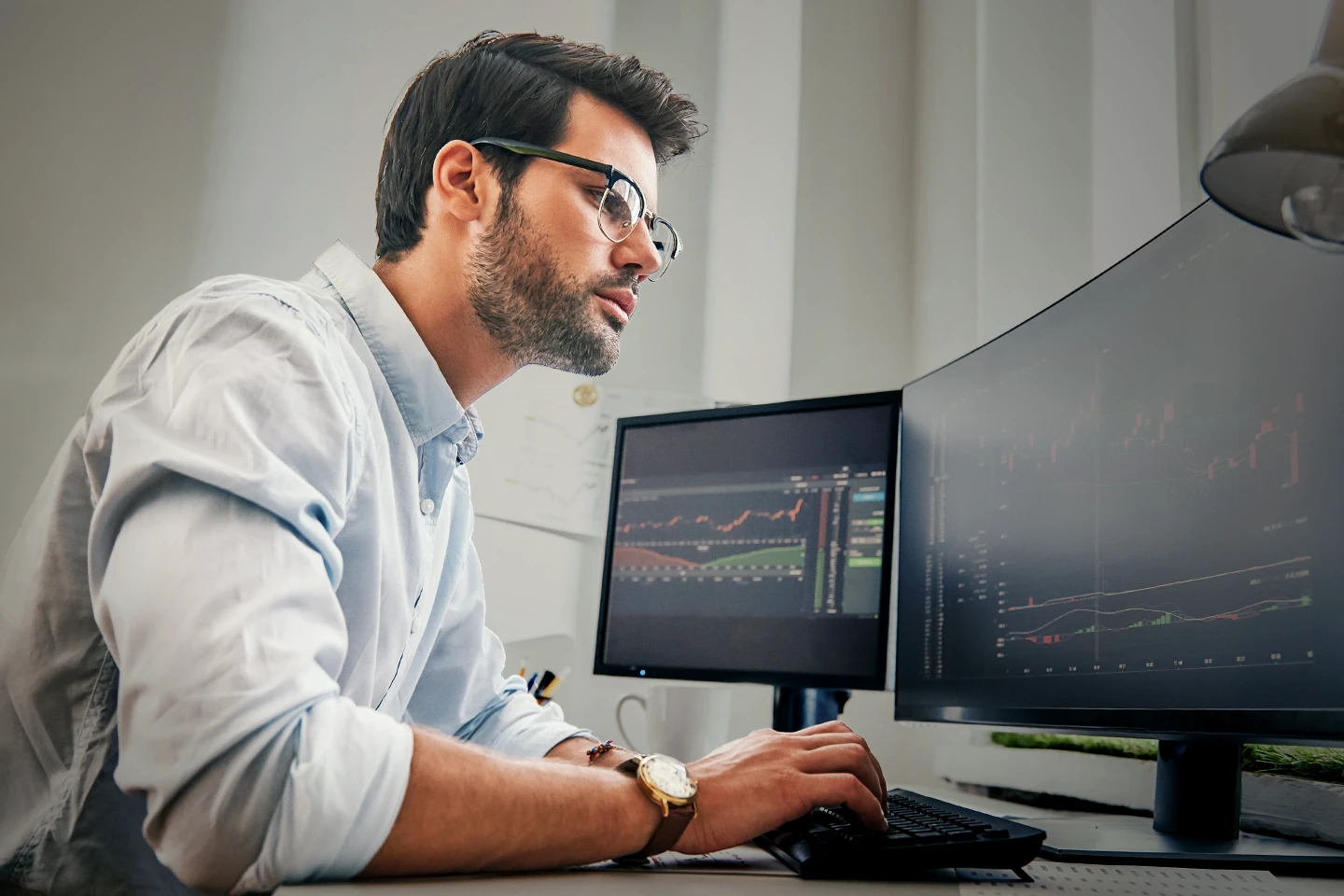 A CMT charterholder reviewing trading charts on two monitors at his desk