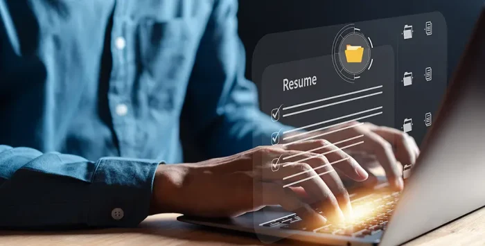 A man on his laptop adding his new CFA charterholder credential to his resume