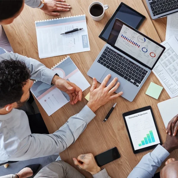 Group of professionals analyzing financial reports and CFA exam questions on laptops and tablets