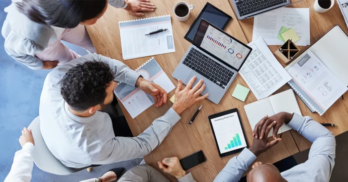 Group of professionals analyzing financial reports and CFA exam questions on laptops and tablets