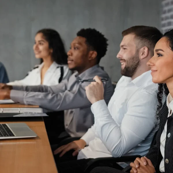 A group of CFA Level 1 candidates following the best CFA Level 1 mastery guide, complete with a study plan and mock exams, using laptops and notes in class.