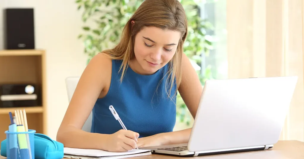 Candidate following an 18-month CFA Level 1 study plan while taking notes and studying on laptop.