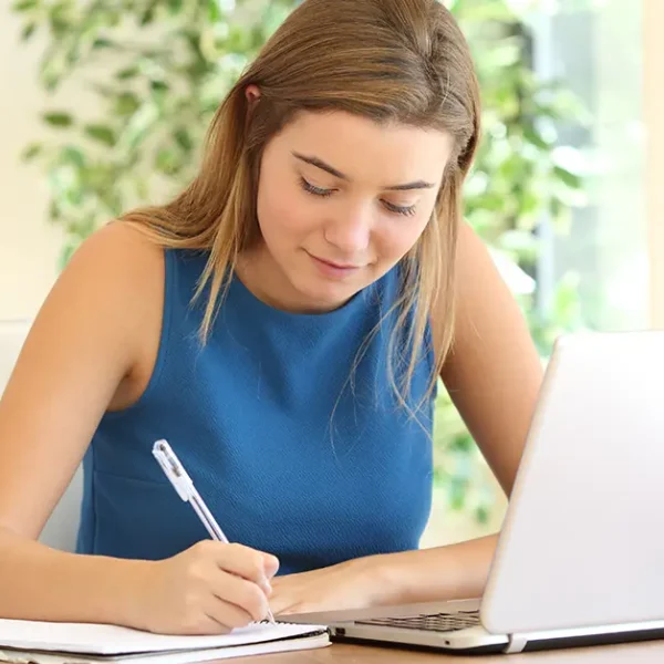 Candidate following an 18-month CFA Level 1 study plan while taking notes and studying on laptop.